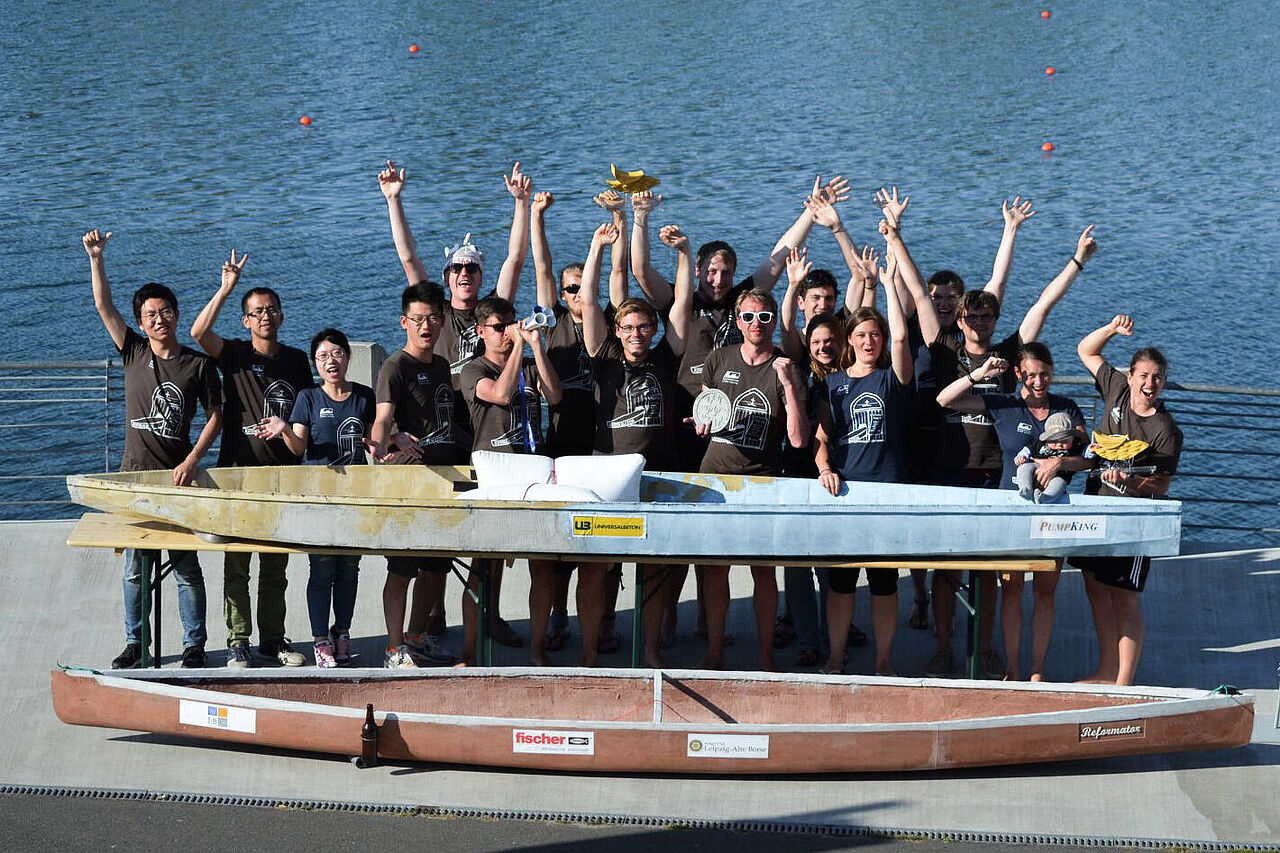 Group picture of the concrete canoe team in front of a river with a canoe