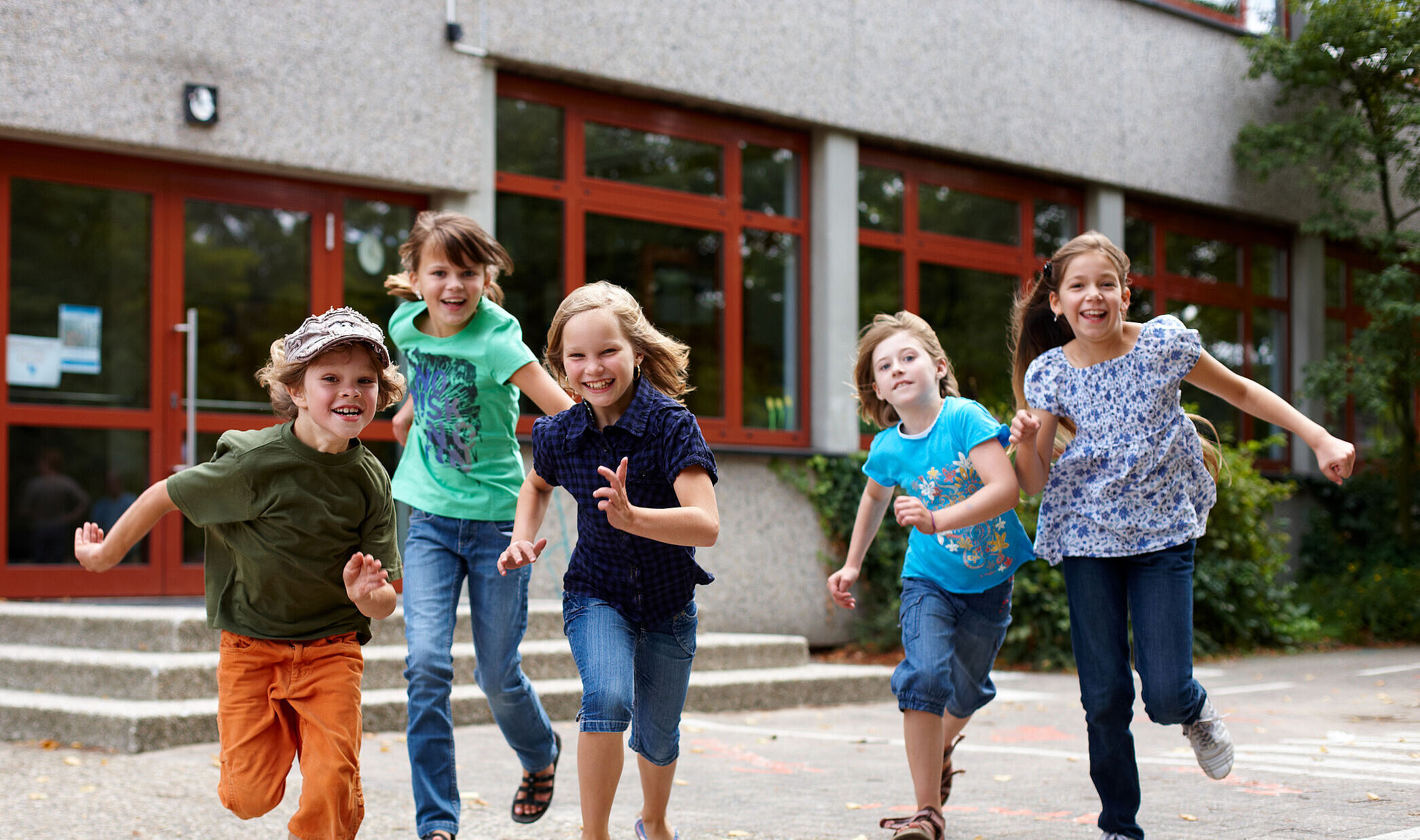 Eine Gruppe aus fünf Kindern rennt gemeinsam auf die Kamera zu.