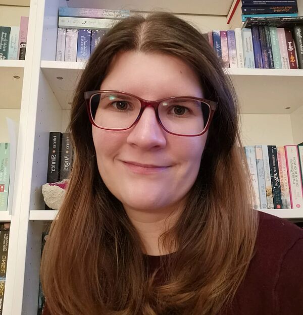 Anne-Sophie Brühl sitzt vor einem Bücherregal