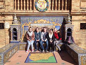 Sebastian Ehrhart sitzt mit vier anderen Studenten und Studentinnen vor einem bunten Mosaik.