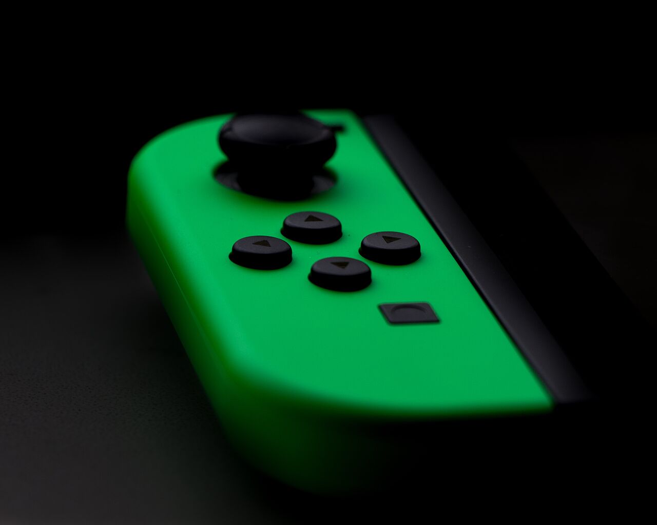 grüner Nintendo Switch Controller vor schwarzem Hintergrund