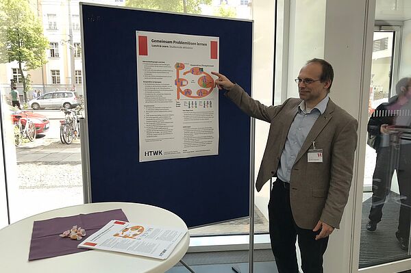Junger Mann zeigt auf ein Plakat