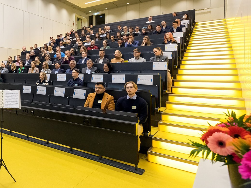 Blick in einen gut gefüllten Hörsaal mit einer Person vorn am Pult.