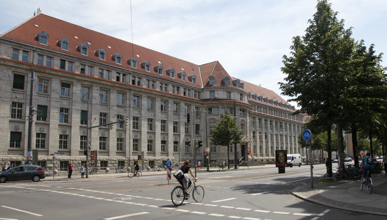Von der anderen Straßenseite seitlich fotografierte Vorderansicht des Forschungszentrums am Campus der HTWK Leipzig. Im Vordergrund ist ein Fahrradfahrer zu erkennen.
