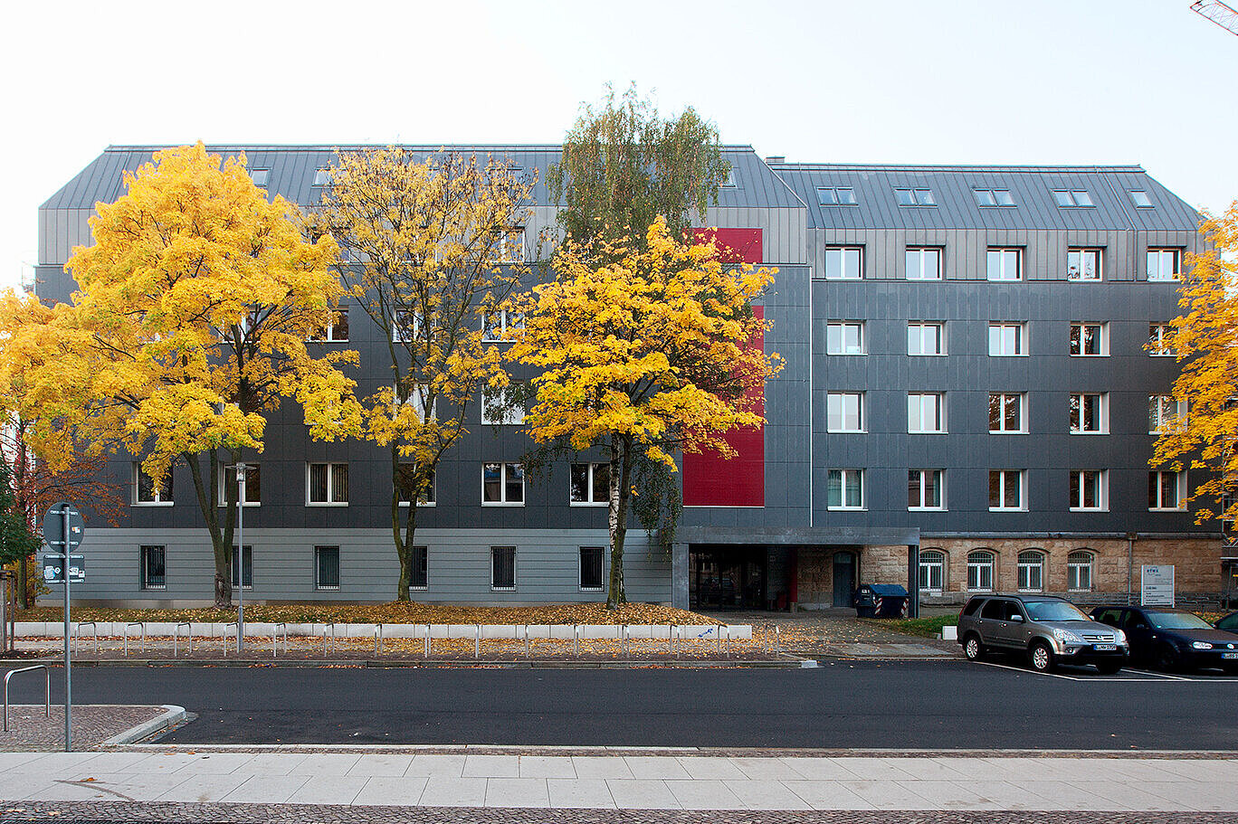 Zuse-Bau (Foto: HTWK Leipzig) Von der anderen Seite fotografierte Frontalansicht des Zuse-Baus. Vor dem Gebäude sind Bäume mit herbstlich gelben Blättern zu sehen.