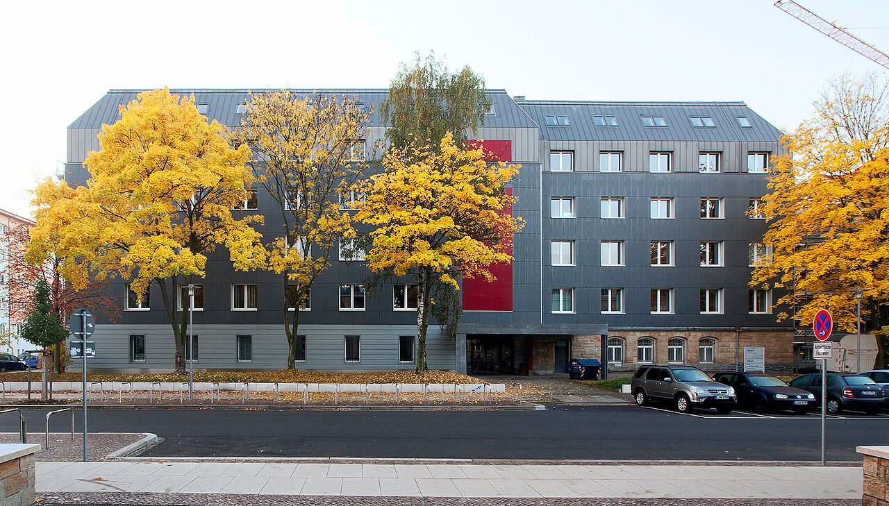 Von der anderen Seite fotografierte Frontalansicht des Zuse-Baus. Vor dem Gebäude sind Bäume mit herbstlich gelben Blättern zu sehen.
