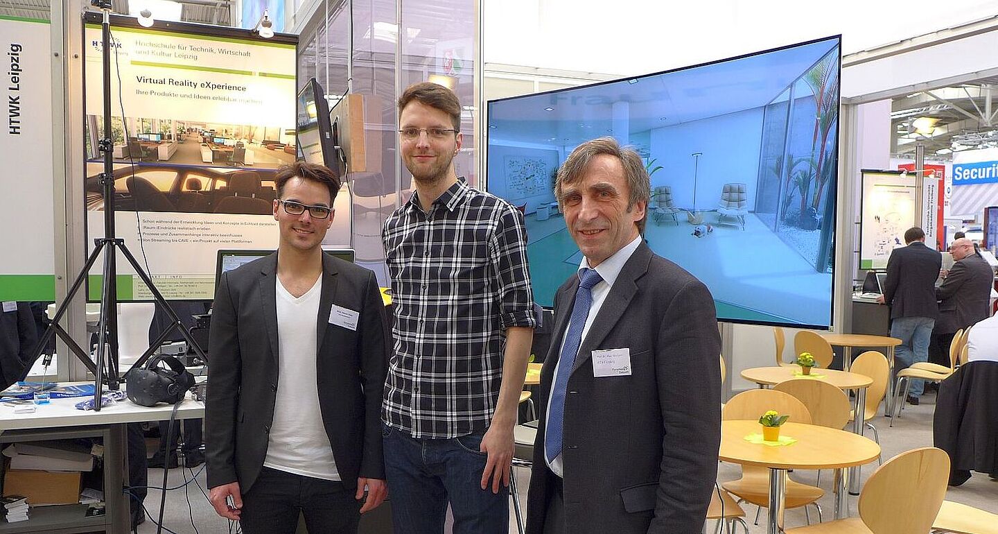 Ein Team um Prof. Hänßgen bei der CeBIT (Foto: Klaus Bastian) Zwei Studierende und Prof. Hänßgen stehen vor dem Messestand der HTWK Leipzig bei der CeBIT in Hannover