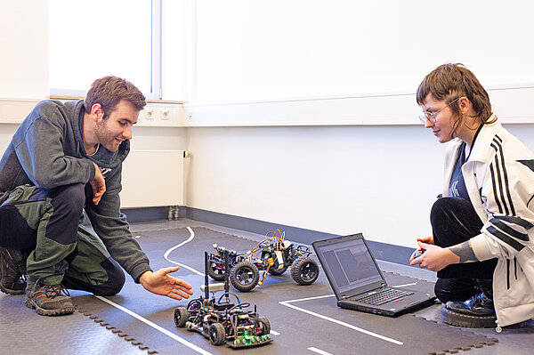 Zwei Studierende testen selbstfahrende Modellfahrzeuge