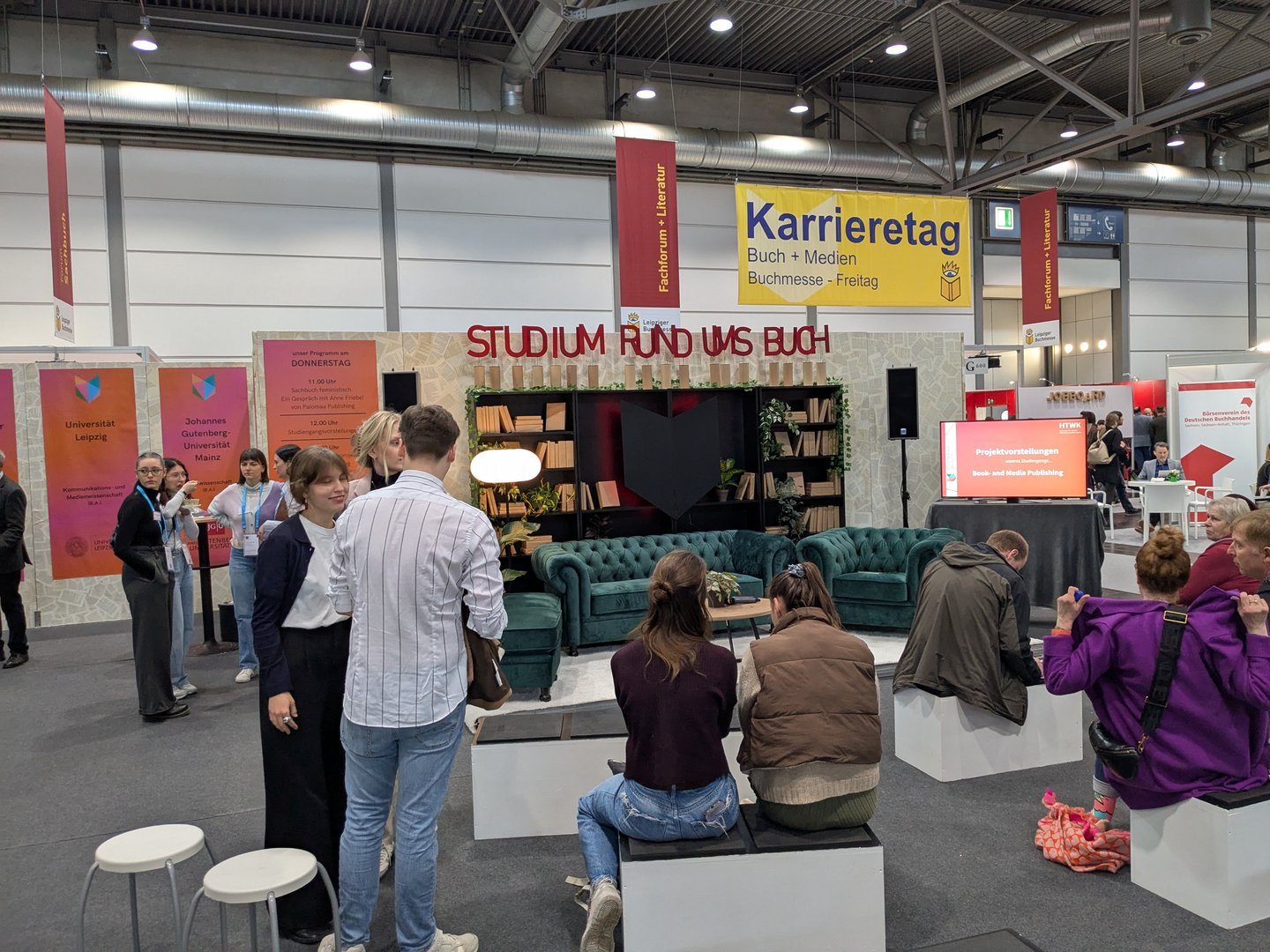 Menschen an Messestand vor Sofa