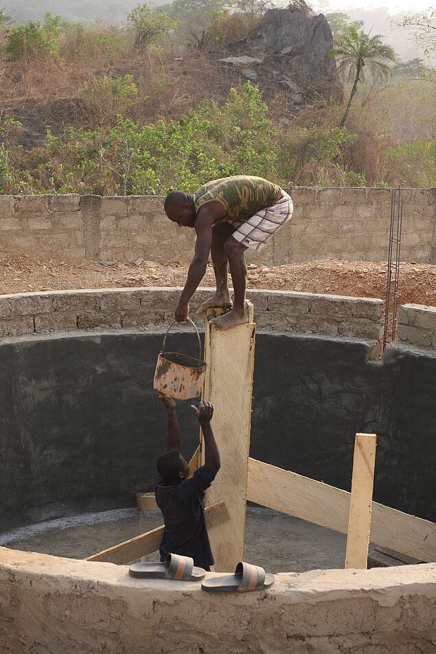 Bild von den Bauarbeiten an der Zisterne mit zwei einheimischen Arbeitern.