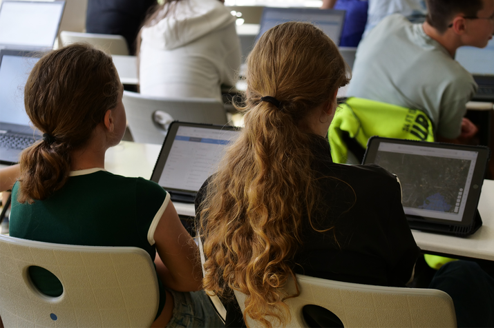 Schülerinnen sitzen vor Tabletts mit GIS-Daten - Aufnahme von hinten in die Semiargruppe
