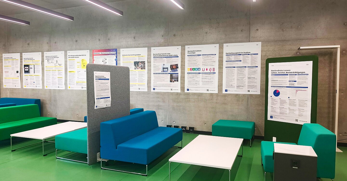 Gesamtüberblick an einer grauen Betonwand sind Poster in Größe A0 in einer Reihe aufgehangen, davor sind Sitzmöbel, Tische und Trennwände zu sehen, die zum öffentlichen Arbeitsbereich der Hochschulbibliothek gehören