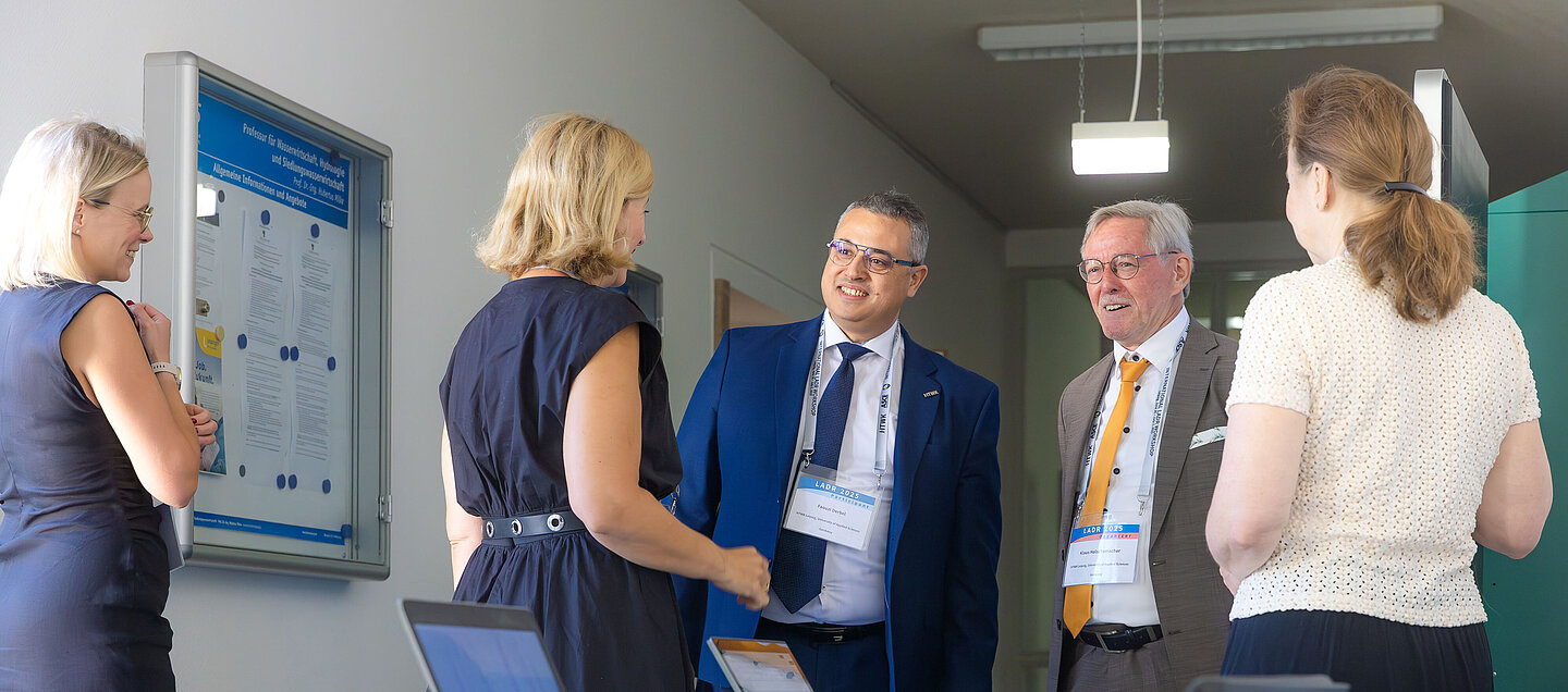 Männer und Frauen stehen um einen Tisch herum und unterhalten sich