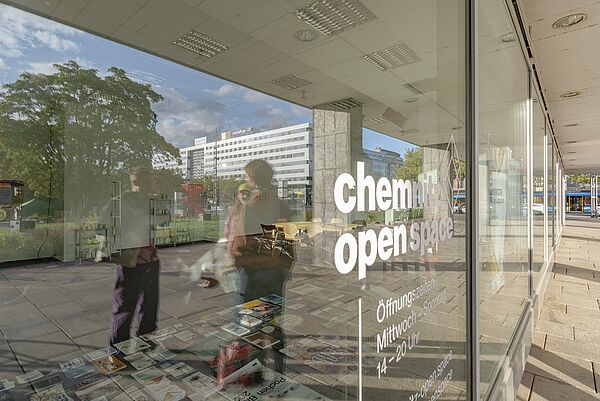 Spiegelung in einer Scheibe: Menschen und Schrift "Chemnitz open Space")