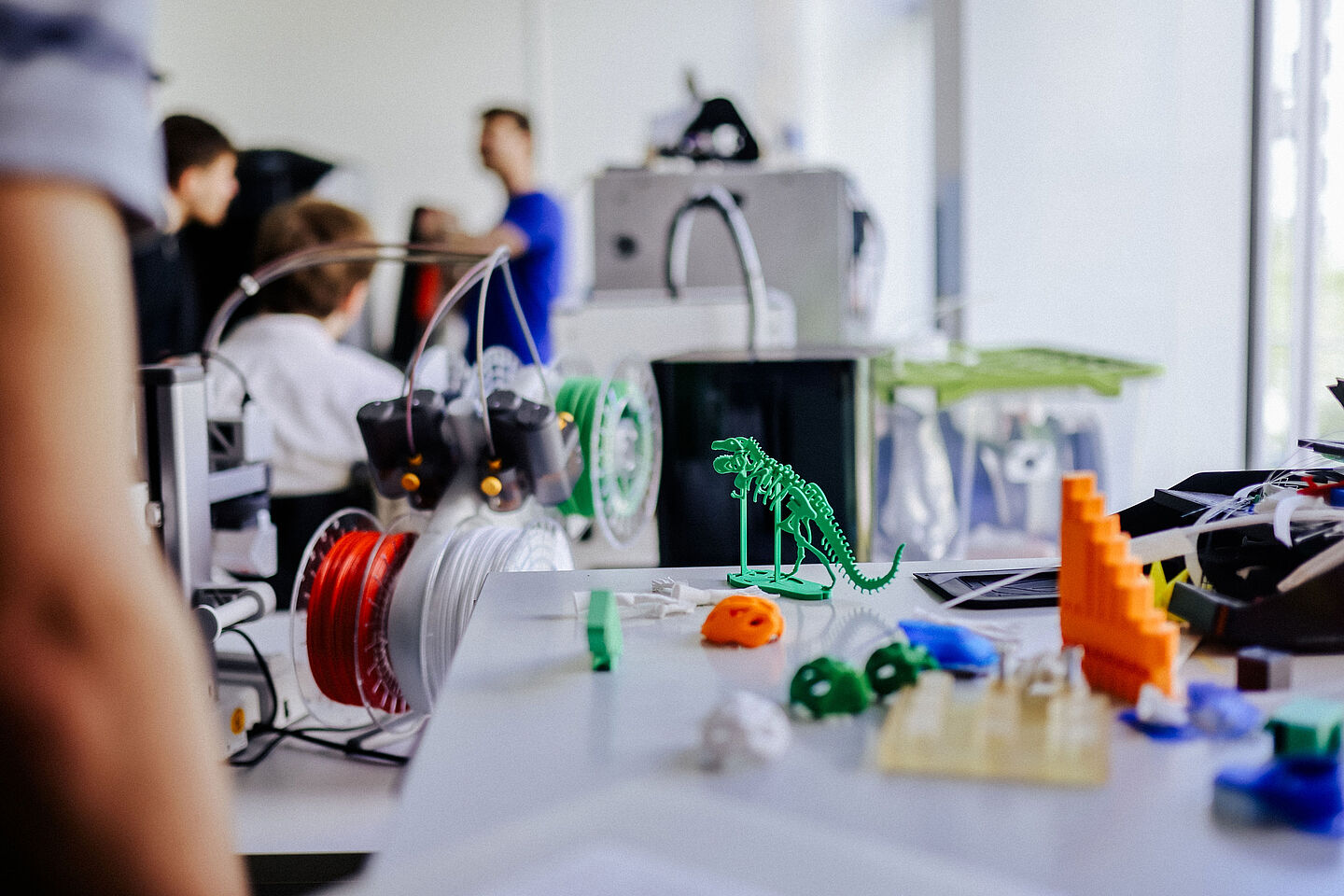 3D-Druck zum Ausprobieren (Foto: Anne Schwerin/HTWK Leipzig) im Vordergrund bunte 3D-gedruckte Teile, im HIntergrund unscharf Personen