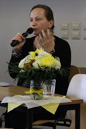 eine Frau mit Mikrophon spricht auf einem Podium 