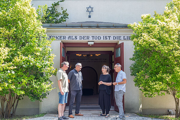 Vier Personen stehen vor dem Eingang der Trauerhalle am Neuen Israelitischen Friedhof Leipzigs