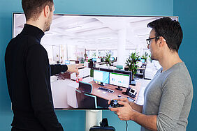 Die LeFx-Geschäftsführer Hannes Finke und Tom Micklich vor einer interaktiven VR-Simulation eines Großraumbüros.