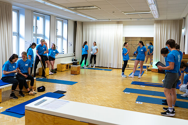 Gruppe von Menschen in Sportkleidung in Raum mit Matten