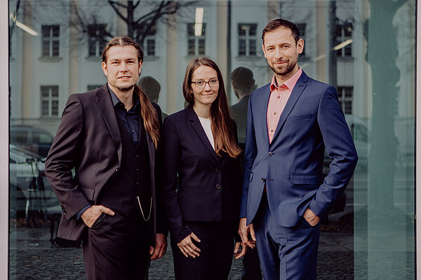 Das Gründungsteam IEXB: Markus Fischer, Yvonne Heym und Gunter Hahn Das Team der IexB vor einer Glaswand.