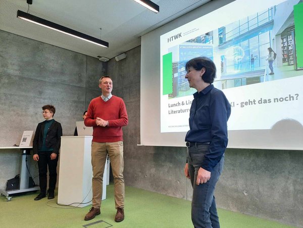 drei Personen vor einer Präsentation an einer Wand