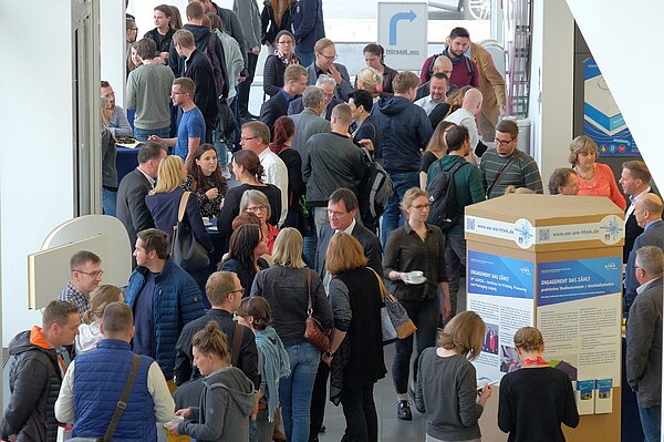 Viele Menschen stehen im Foyer der Hochschule und unterhalten sich.