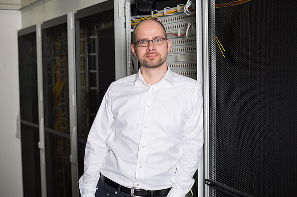 Dr.-Ing. Gerold Bausch steht in einem Serverraum