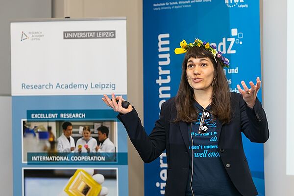 Eine Frau mit Blumenkranz im Haar gestikuliert mit den Händen