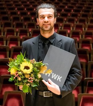 Preisträger hält die Urkunde des Dissertationspreises und einen Blumenstrauß in der Hand