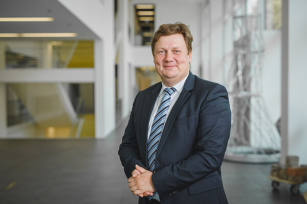 Prof. Markus Krabbes. (Foto: Stephan Flad/HWTK Leipzig) Mann in großem Raum (Markus Krabbes im Foyer Nieper-Bau der HTWK Leipzig)