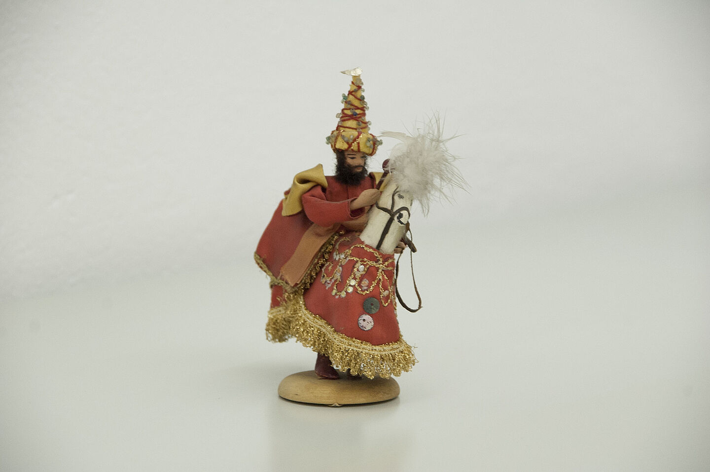 Reiter aus dem HTWK-Archiv (Foto: HTWK Leipzig) Zu sehen ist eine kleine Figur eines Mannes mit dunklem Vollbart. Er trägt einen spitzen, verzierten Hut und ein rotes, weites Gewand. Er sitzt auf einem Holzpferd, das eine reich verzierte Decke trägt.