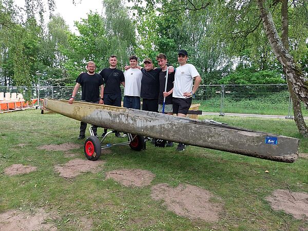 Gruppe mit Kanu aus Beton steht auf Wiese