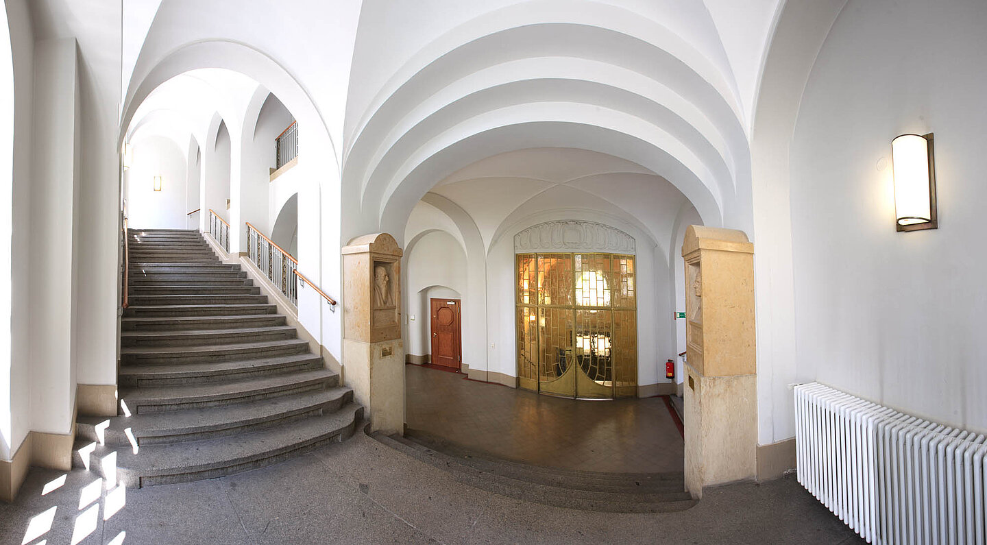 Geutebrück-Bau Innenansicht. Ein Treppenhaus. Links gehen Stufen hoch, in der Mitte ist ein Gang, die Decke ist ein Gewölbe.