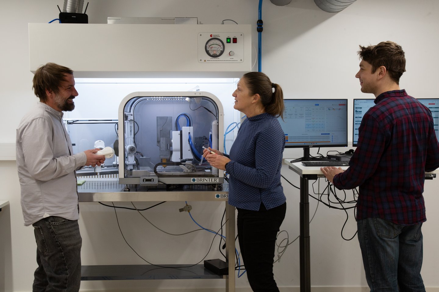 Drei Personen stehen am 3D-Drucker