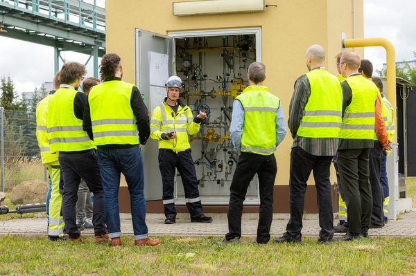 8 Männer unterhalten sich vor einer Gasregelanlage