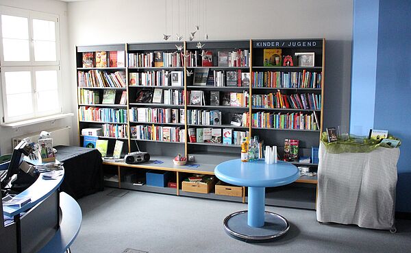 Buchhandlung mit einem Tresen, Bücherregalen und Sitzflächen zum Verweilen.