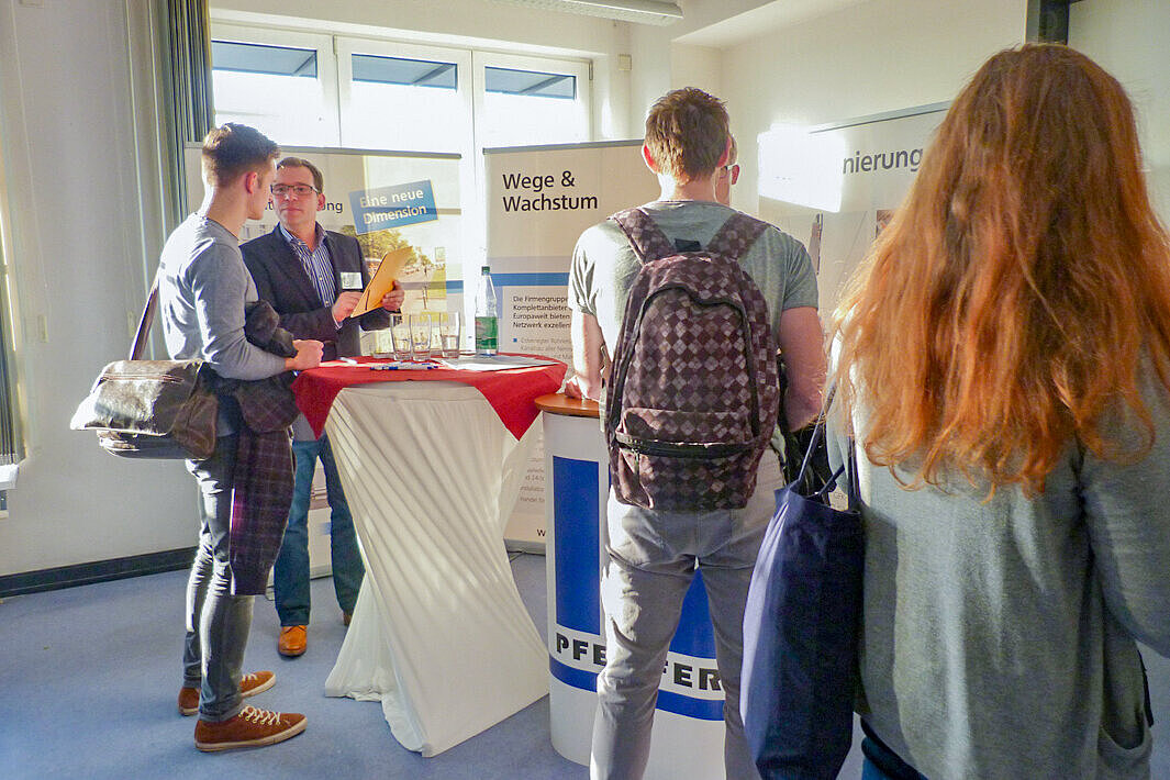 Mehrere Firmenstände mit Vertretungen und interessierten Studierenden davor