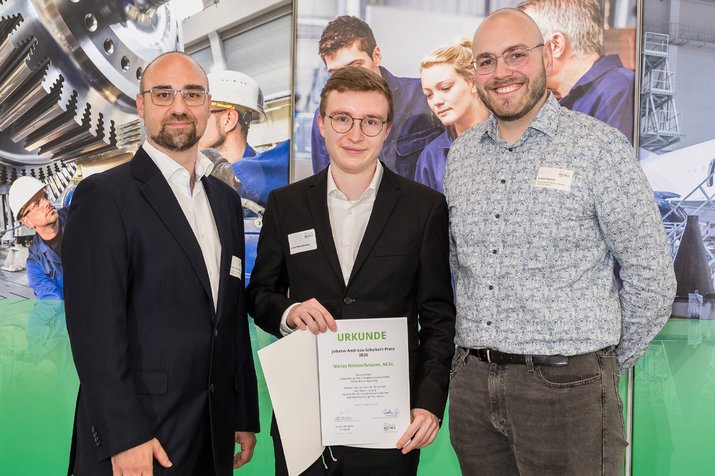 Gruppenfoto, Preisträger in der Mitte hält Urkunde zwischen den Händen