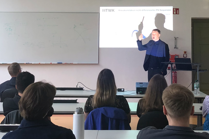 Prof. Krondorf an der Projektionsfläche eines Beamer zu sehen im Seminarraum, im Vordergrund Zuhörende