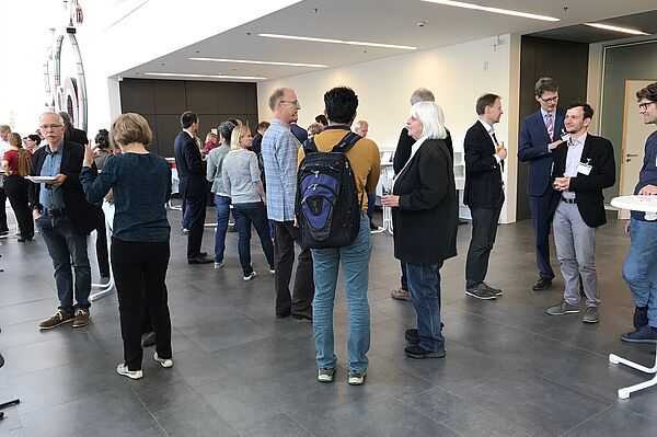 Leute unterhalten sich an Stehtischen im Foyer.