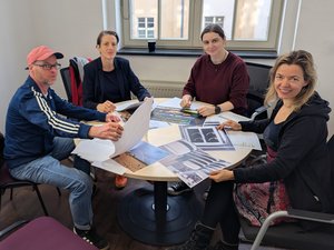 Jury 4 Personen sitzen an einem Tisch, auf dem Bilder liegen