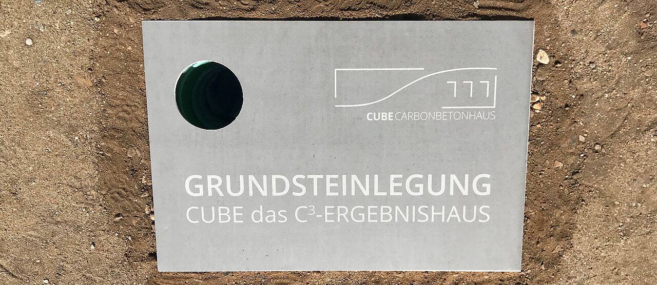 Rechteckiger Grundstein mit einem Loch zum Einlassen der Zeitkapsel. Auf dem Grundstein steht: Grundsteinlegung. CUBE das C3-Ereignishaus.