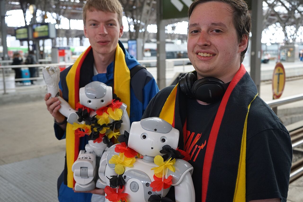 Wieder zuhause: Marvin Jenkel mit Nao-Roboter „Ursula“ (links) und Daniel Weiß mit „Joker“ vom Nao-Team HTWK. (Foto: HTWK Leipzig)