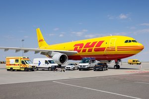 Rettungswagen, Transporter, Roboter-Hunde und ein DHL-Flugzeug stehen auf der Rollbahn