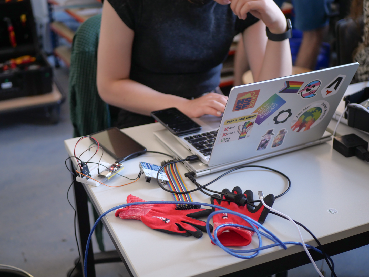 Eine Person programmiert das Bewässerungssystem. Auf dem Tisch vor ihr liegen Kabel.