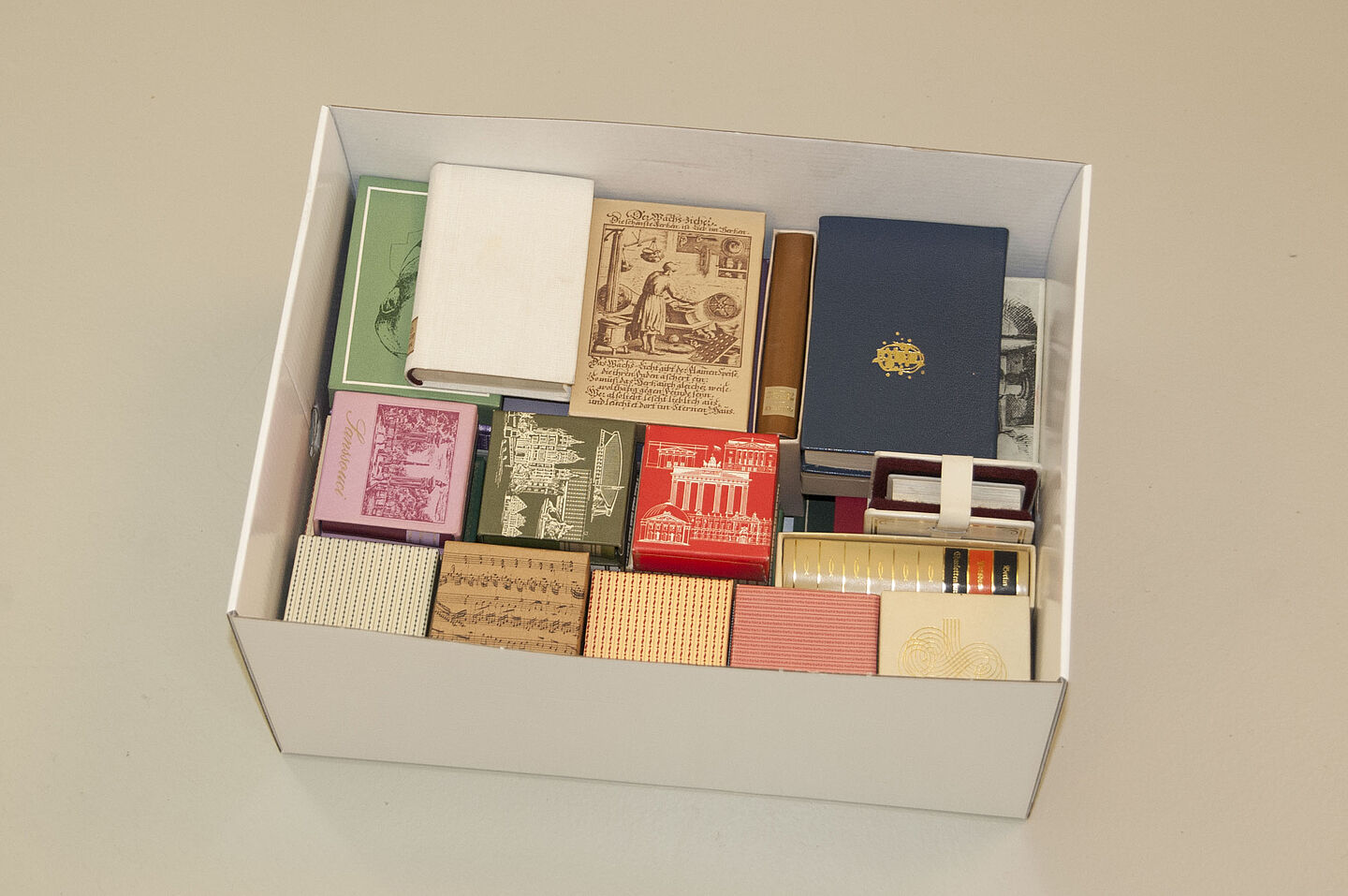 Minibücher aus der DDR im HTWK-Archiv (Foto: HTWK Leipzig) Zu sehen ist ein Karton, in dem sich viele Minibücher aus DDR-Zeiten stapeln. Sie haben verschiedenfarbige Einbände.