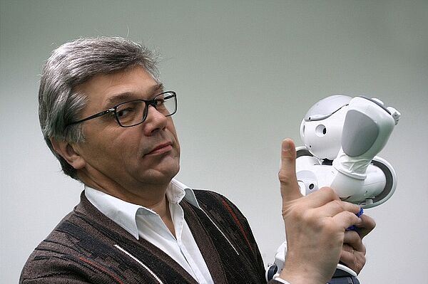 Klaus Bastian mit Fußballroboter Nao Mann mit kleinem Roboter in der Hand