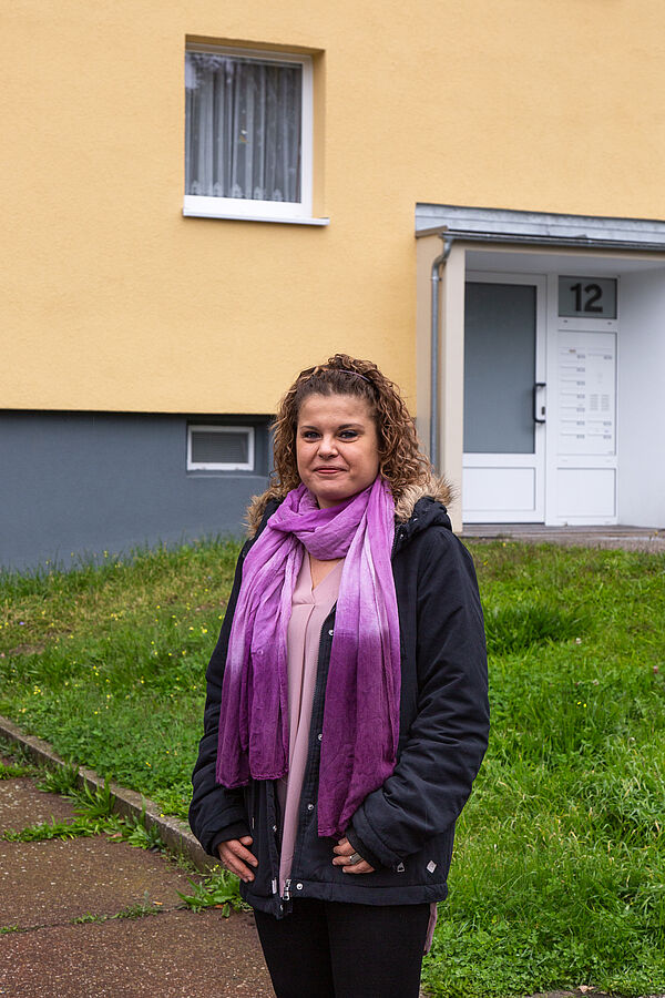 Dr. Marina Block steht vor einem Plattenbau in Leipzig-Lößnig