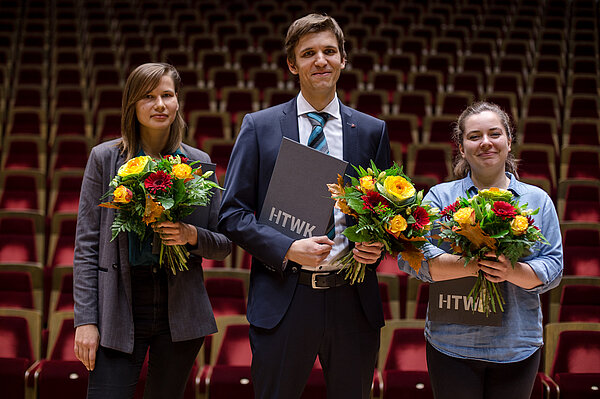 Marina Jostina, Christian Mahlburg, Wiebke Kestler (Foto: Robert Weinhold/HTWK Leipzig) Zwei Frauen und ein Mann je mit Blumenstrauß in der Hand stehen auf der Bühne im großen Saal des Gewandhauses