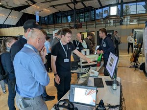 Präsentation auf der Tagung Musikinstrumente Foto von mehreren Person am Ausstellungsstand